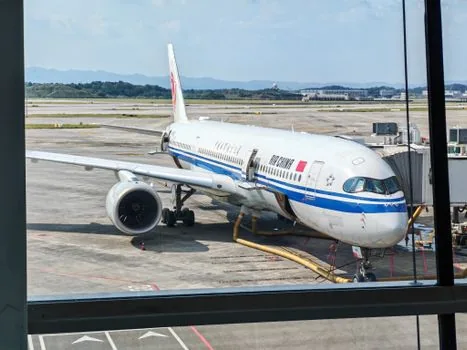 airline gate agent speaking with passenger near jet bridge and carry-on bags