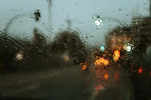 heavy rain falling on a Korean coastal city road, orange traffic cones, police line, cars stopped, documentary news photography, no readable text