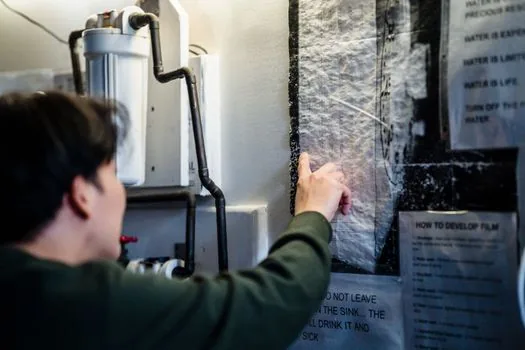 Korean apartment resident photographing water damaged floor, soaked furniture and wall water line after heavy rain, realistic documentary photo, no readable logos