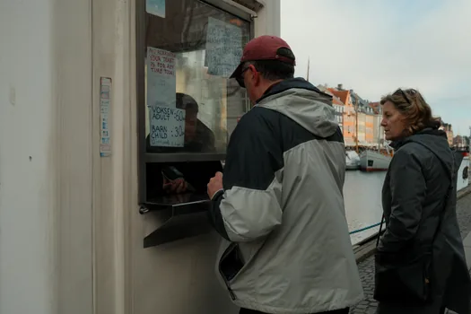 Korean family checking amusement park safety rules near ticket booth, calm documentary lighting, no readable text, no brand logos