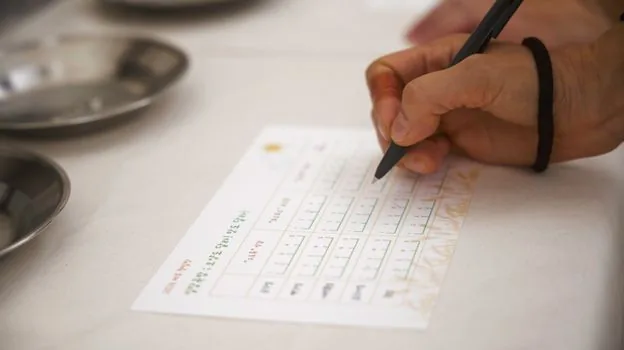 Korean family member checking delegated certificate request documents and ID card at civil service desk | 대리 신청 가능 여부와 신분증 서류를 확인하는 장면