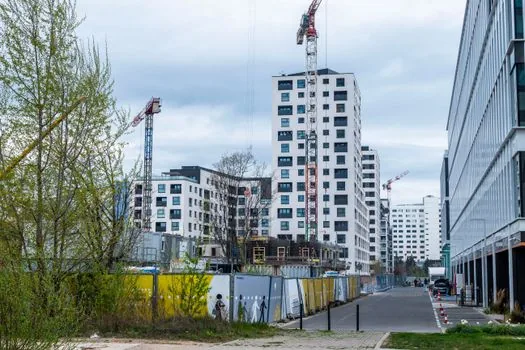 Korean public housing construction inspection scene with officials looking at site map, apartment blocks in background, neutral news photography style