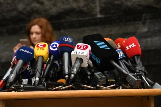 wide shot of empty football press conference room with microphones and national team backdrop, editorial sports news photography, no text