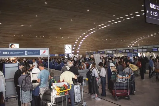airport departure information board with passenger checking terminal and gate number on printed itinerary, realistic Korean travel photo, no logos | 터미널과 출국장 번호를 여정표와 맞춰보는 장면
