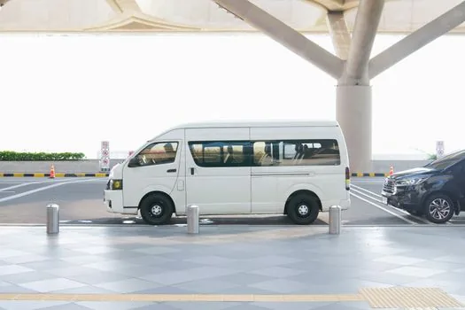 airport police escort van at dawn with blurred figure, reporters behind line, serious social news photography, no close-up face | 국내 송환 뒤 수사 이동 | 인천공항 송환 보도 분위기를 재구성한 장면