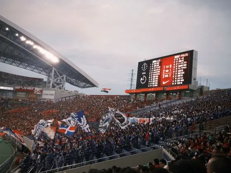 football match scoreboard showing 4-0 result in a rainy night stadium, red home team atmosphere, no real logos, editorial sports lighting
