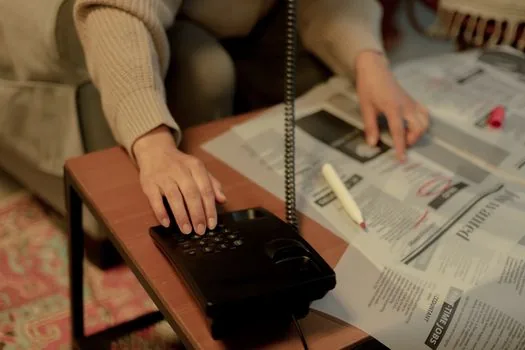 Korean person checking suspicious text message, bank card, police cyber report note and 118 helpline memo on desk, realistic public safety editorial photo | 스팸 문자 피해 대응 연락처를 정리하는 장면
