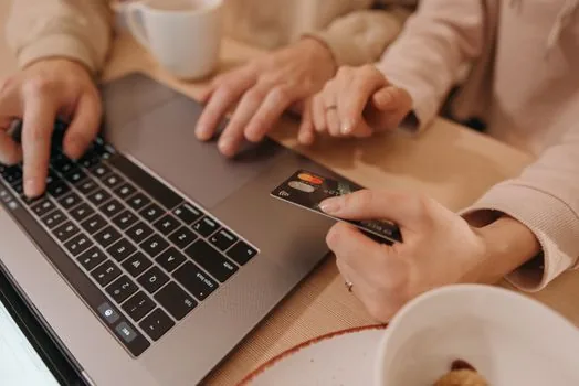 Korean taxpayer using laptop for local tax payment, vehicle registration card and phone authentication nearby, clean desk, no readable personal data | 위택스 자동차세 연납 신청 전 차량정보를 확인하는 장면