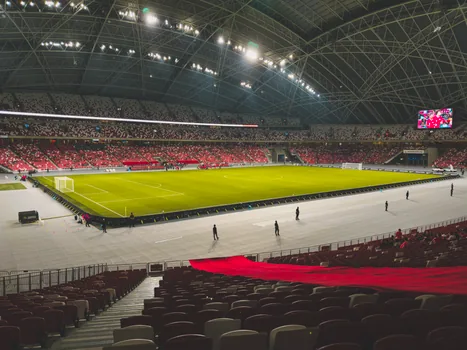 Nagoya stadium exterior with athletes and broadcast vans before Asian Games opening, editorial sports image