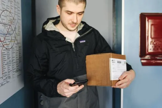 Overseas parcel tracking checklist with smartphone notification and blurred customs portal on laptop, Korean home office, privacy-safe realistic photo
