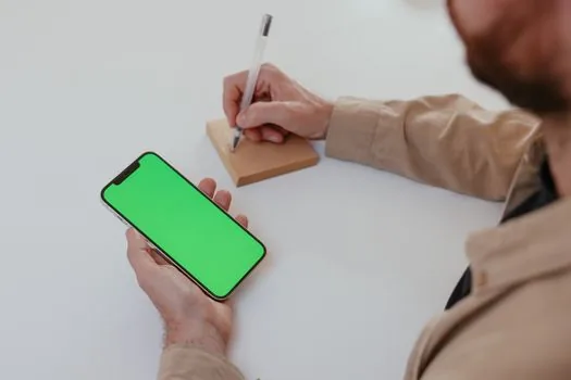 person checking emergency safety app on phone beside handwritten home office school shelter route note, calm Korean household scene, bright natural light | 안전디딤돌 앱과 가족 대피 동선을 같이 확인하는 장면