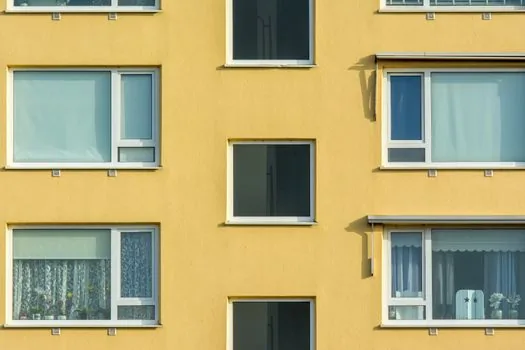 resident checking construction permit documents on laptop beside apartment window, Korean neighborhood context, clean editorial photo style