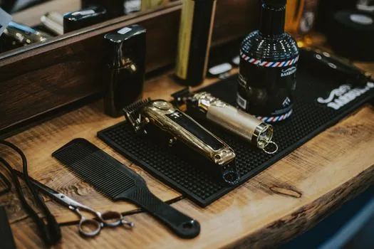 smartphone showing anonymized review response beside hair cutting scissors and comb on salon counter, editorial news photo style, no readable brand text