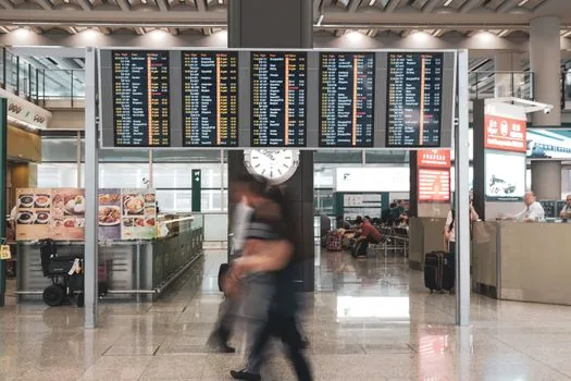 traveler at airline service counter arranging replacement flight and hotel receipt, calm airport terminal, no readable private data | 결항 뒤 대체편과 숙박비 확인 | 항공사 카운터에서 일정 변경을 확인하는 장면
