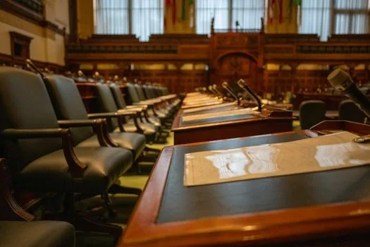 United Nations assembly hall with distant podium, diplomatic folders on table, no readable logos, serious editorial lighting | 젤렌스키 대통령의 유엔총회 공개 발언을 설명하는 장면